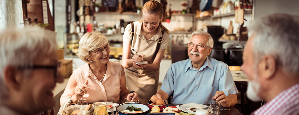 Image of a group of seniors ordering from a server at a restaurant